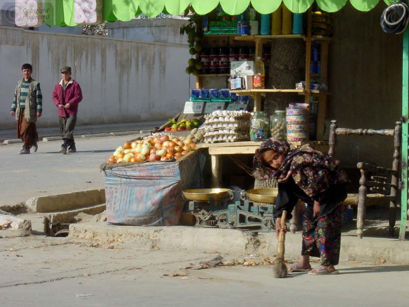 Little Girl sweeping in front of Shop 